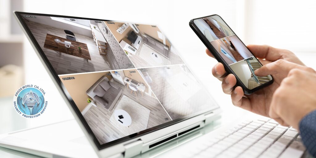 Persona utilizando un portátil y un teléfono móvil para ver múltiples cámaras de seguridad en vivo, mostrando un sistema de vigilancia remoto.
